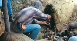 先史時代の技法で作った陶器をオーブンから取り出します